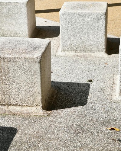 A group of abstract concrete blocks casting shadows on a sunny day.